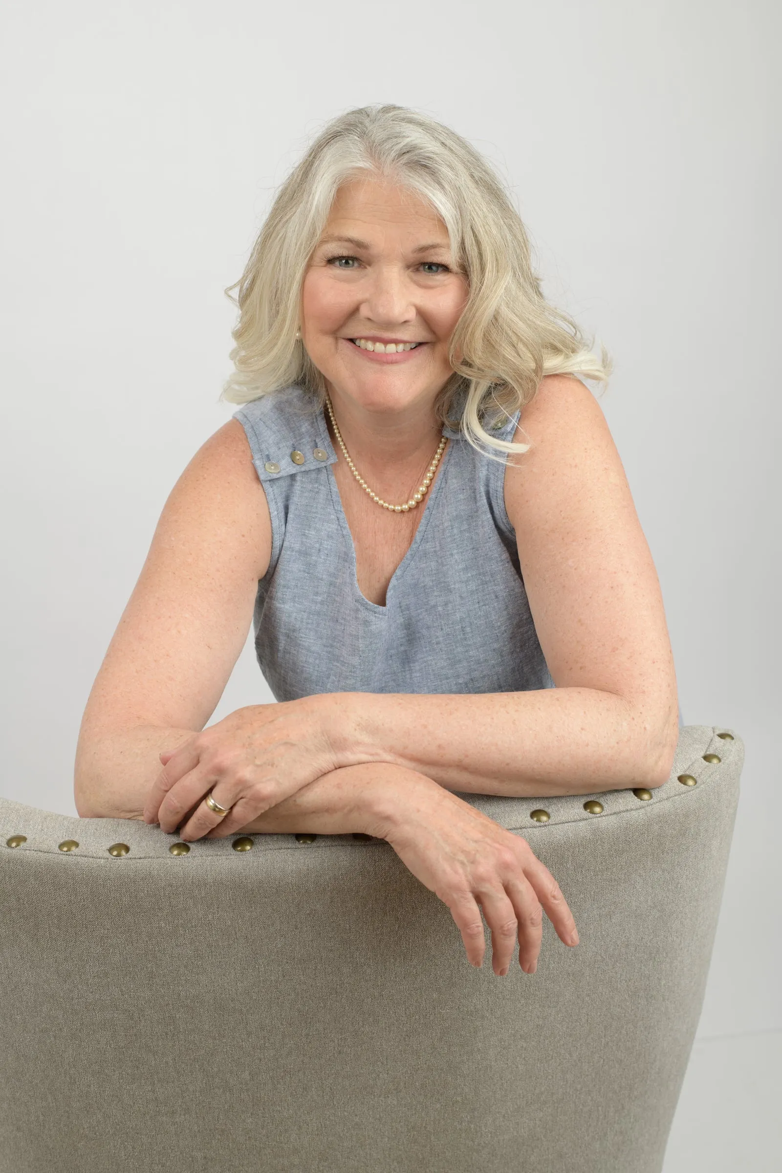 Liz Hannibal Drury smiling, leaning on the back of a chair